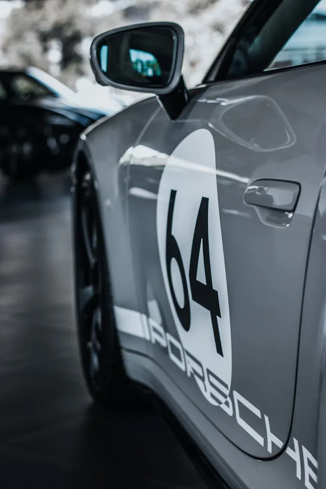 Grey sports car with retro racing roundel number 64 and side script decals